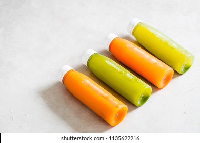 Row of plastic bottles of cold-pressed unprocessed fruit and vegetable juices, from above, light gray table. Body cleance, fast concept. Minimalism food photography. Copyspace