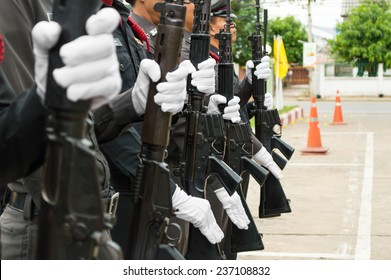 A Row Of Police Wearing White Gloves Holding A Gun To Salute.