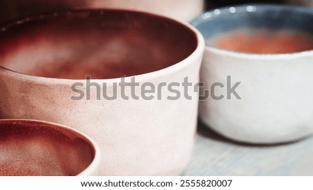 A row of pots with different colors and patterns. The middle pot is the tallest. The bottom pot is the lightest