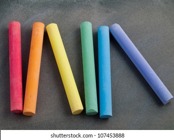 Row Of Rainbow Colored Chalk On A Blackboard