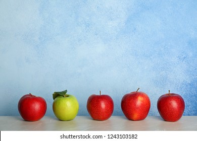 Row Of Red Apples With Green One On Table. Be Different