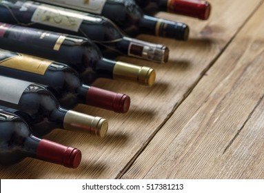 Row of red dry wine bottles on wooden background. Low depth of field. 