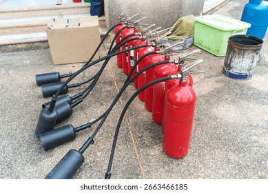 A row of red fire extinguishers lined up, showcasing essential safety equipment for emergency situations. Ideal for training and safety protocols.