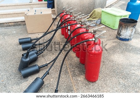 A row of red fire extinguishers lined up, showcasing essential safety equipment for emergency situations. Ideal for training and safety protocols.