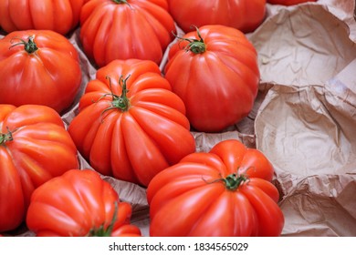 Row Of Red Fresh Heirloom Tomatoes Arranged On Paper At Stall In Farmer Market.