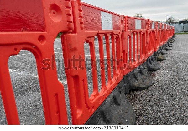 Row of red temporary weighted plastic barriers in\
car park