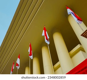 a row of red and white flags between the pillars of the building