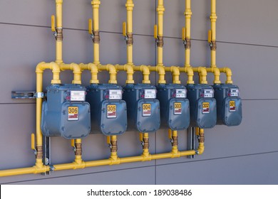 Reihe von Haushalts-Erdgaszählern und Gelben Rohrleitungen an der Außenwand zur Messung des Energieverbrauchs von Haushalten