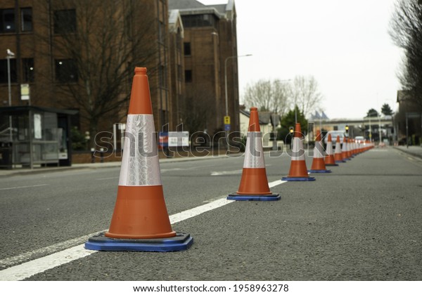 A\
row of road safety cones with buildings in a\
background
