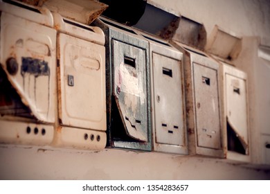 A row of rusty mailboxes. Angled close-up outdoor shot.
