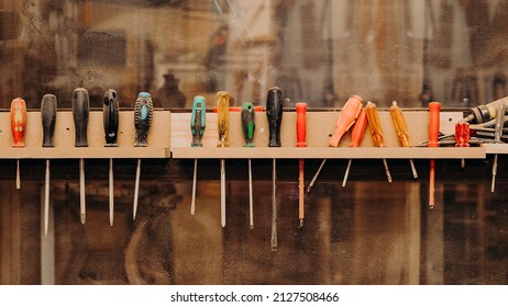 Row Of Screwdrivers Fastened On Dusty Shelf