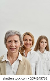 Row Of Serious Caucasian Family Of Three Female Generations Looking At Camera. Age And Generation Concept. Grandmother, Mother And Granddaughter. Isolated On White Background In Studio. Copy Space