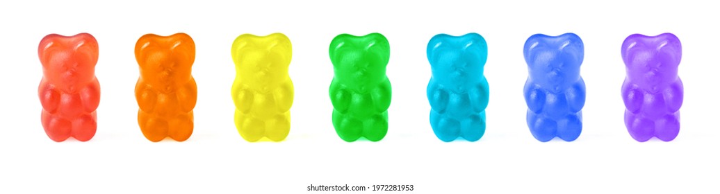 Row of seven gummy bears painted in rainbow colors isolated on white
