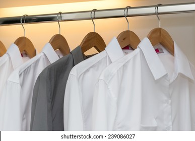 Row Of Shirts Hanging On Coat Hanger In White Wardrobe