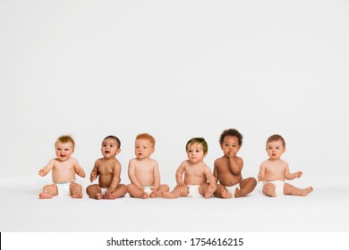 Row of six multi ethnic Babies smiling in studio