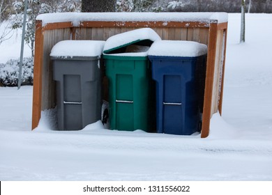 Row Of Snow Covered Compost, Recycling, And Garbage Dumpsters, In A Winter Trash Pick Up Scene