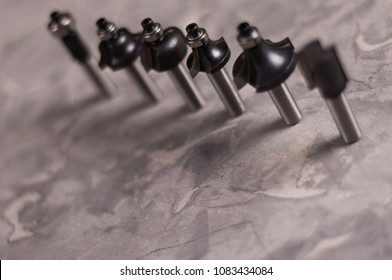 Row Of Lot Of Steel Router Bits For Milling Cutter On Old Broken Worn Gray Concrete Floor With Copy Space