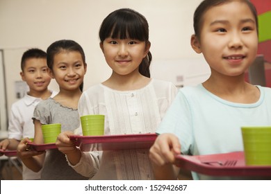 Row Of Students Standing In Line In School Cafeteria