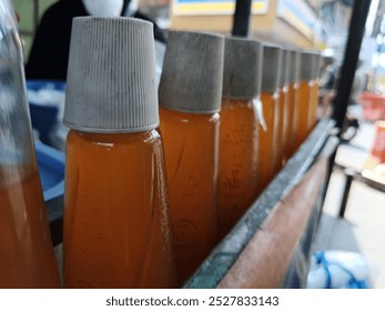 A row of syrup bottles in an array  neatly arranged on a wooden shelf,  ideal for culinary enthusiasts 