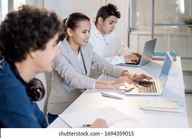 Row of teenage classmates sitting by desk at lesson and discussing online data while getting ready with presentation of their project - Shutterstock ID 1694359015