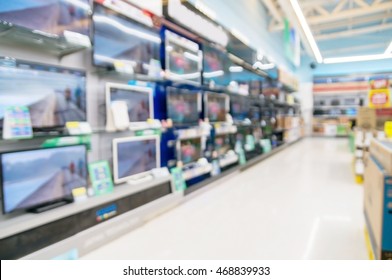 Row Of Television On Shelf In Hypermarket, Supermarket Or Electronic Home Appliance Shop. Abstract Blur Or Defocus Background.