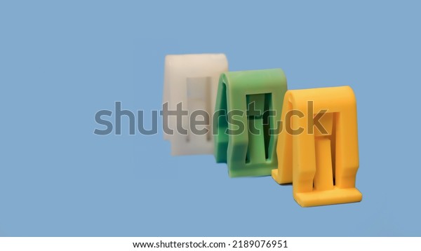 Row of three automotive Interior parts\
plastic clips on blue\
background.