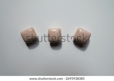 Row of three pink rectangular pieces of chewing gum