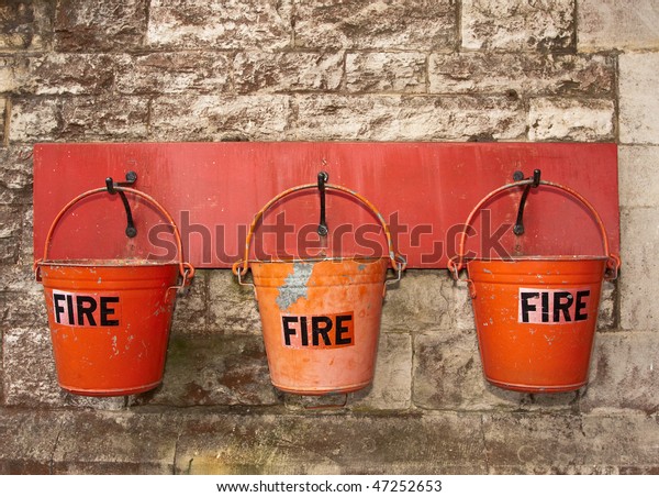 A row of three red fire buckets hung on the wall\
of an old railway station