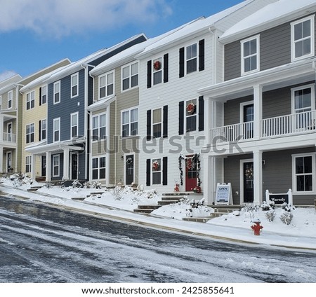 Row of townhomes with a street in front of them. Season is winter with snow on the sidewalks and townhouses. Home ownership or rental units in a housing community for investment portfolio.