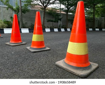 A row of traffic cones on the road. These objects are temporary traffic control devices for directing and avoiding sections of the road being repaired or diverting traffic.