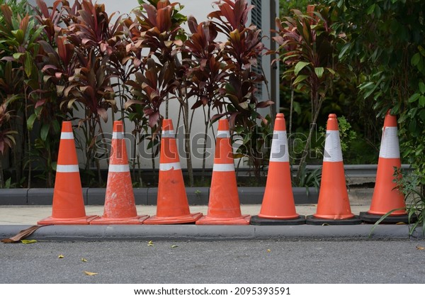 A row of Traffic\
safety cone with white and orange  put temporary on the border of\
street for block the path to repair or decorate the place in the\
garden or the street.