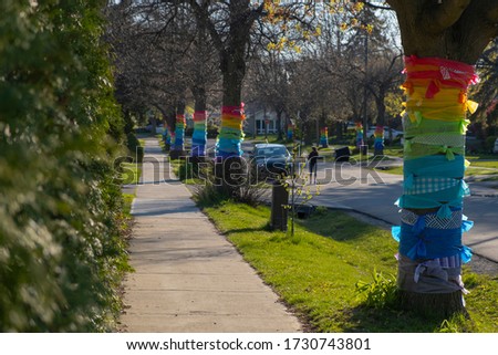 Row of trees wrapped in rainbow colored ribbons in appreciation and support of front line, essential workers, healthcare providers and first responders during corona virus  outbreak. Selective focus.