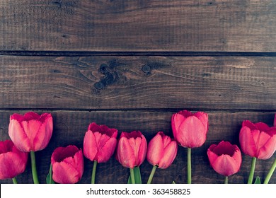 Row of tulips on wooden background with space for message.  Mother's Day background. Top view