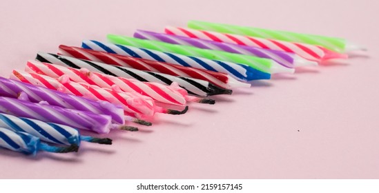 A row of unlit and lighted candles isolated on pink background