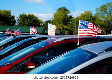 A row of US flags mounted on automobiles at a used car business.