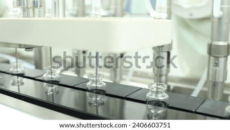 a row of vaccine empty injection glass vials moving filling process with liquid medicine for medicine production in a pharmaceutical injectable manufacturing company