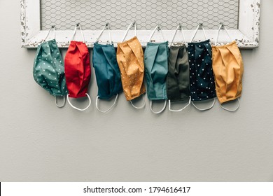 A row and variety of colorful protective face masks hanging on a home bulletin type clipboard for going back to work or back to school  for easy access with copy space - Shutterstock ID 1794616417