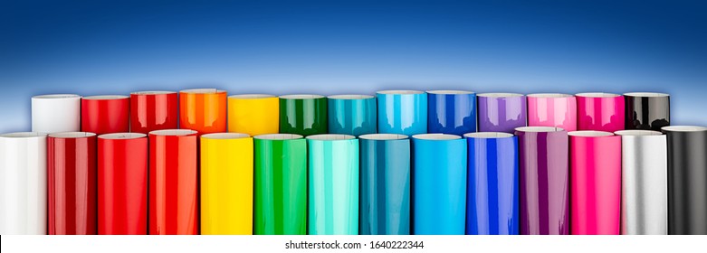 Row of various rainbow colored vinyl car wrapping or plotter cutting sticker foil film rolls on blue white wide panorama banner background