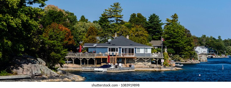 Row of waterfront cottages and homes perched on rocky outcrops in the Thousand Islands, St. Lawrence River area.
