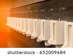 A row of white porcelain urinals.Selective focus point in public toilets with morning light.