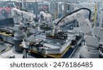 Row of White Robotic Arms at Automated Production Line at Bright Modern Factory. Industrial Robot Arms Assemble Lithium-Ion EV Battery Pack.  Electric Car Manufacturing Inside Automotive Smart Factory