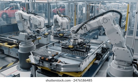 Row of White Robotic Arms at Automated Production Line at Bright Modern Factory. Industrial Robot Arms Assemble Lithium-Ion EV Battery Pack.  Electric Car Manufacturing Inside Automotive Smart Factory