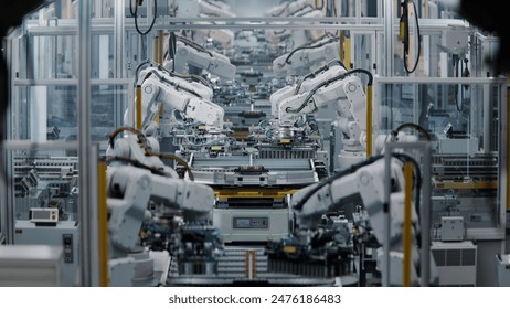 Row of White Robotic Arms at Factory. Lithium-Ion EV Battery Pack Production at Large Automated Assembly Line at Bright Factory Equipped With Industrial Robot Arms. Electric Car Manufacturing. - Powered by Shutterstock