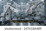 Row of White Robotic Arms at Modern Factory. Lithium-Ion EV Battery Pack Production at Automated Assembly Line at Bright Factory Equipped With Industrial Robot Arms. Electric Car Manufacturing. 
