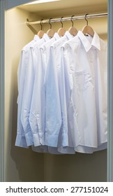 Row Of White Shirts Hanging On Coat Hanger In Wardrobe