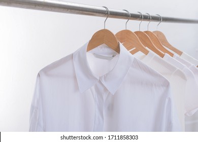 Row Of White T-shirts With White Long Sleeves Shirts Hanging On Wooden Hangers
