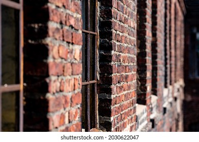 Row Of Windows Of A Ruined Factory Facade With Broken Glass And Corroded Iron In A Red Brick Wall In A Lost Place In Iserlohn Germany. Vanishing Point Perspective Illuminated By Bright Sunlight.