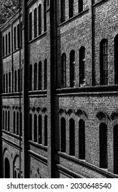 Row Of Windows Of A Ruined Factory Facade Historic Brick Wall In Lost Place In Iserlohn Germany. Vanishing Point Perspective Illuminated By Bright Sunlight. Black And White Greyscale Background.