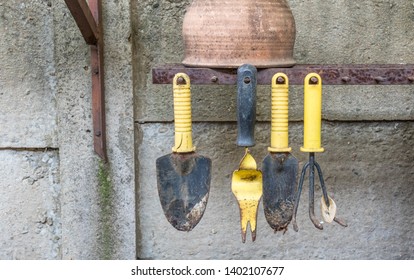 A Row Of Yellow And Black Metal Hand Gardening Tools Isolated Hanging From Spikes With A Gap For A Missing Tool Image With Copy Space