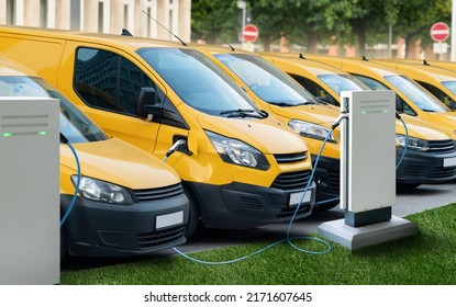 Row Of Yellow Electric Delivery Vans At Charging Stations For Electric Vehicles